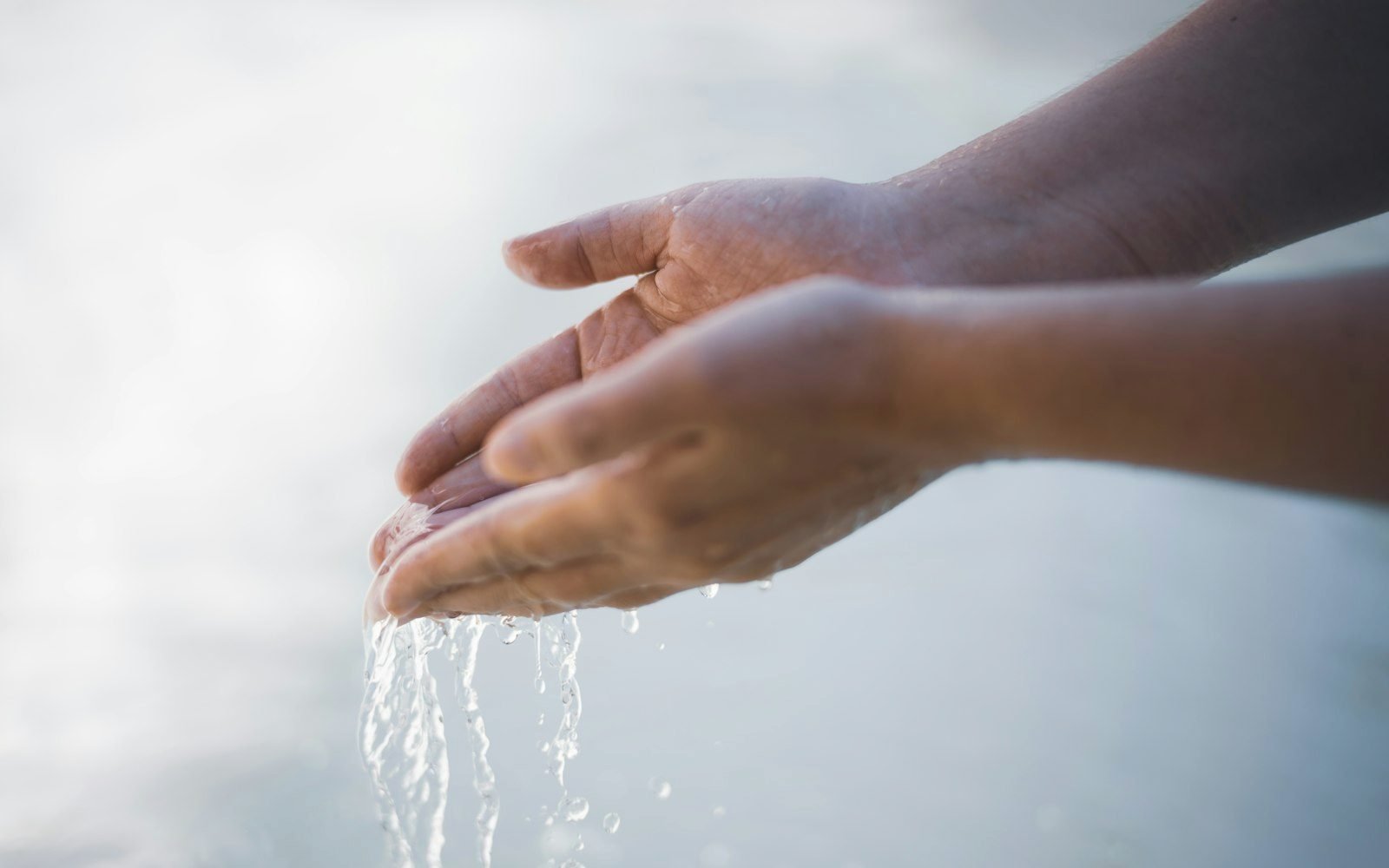 Hands rinsing face at a sink